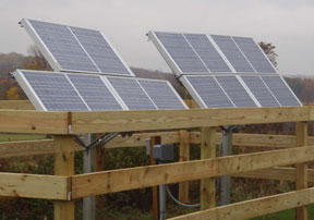 Solar panels supply electricity to water pump in pasture.